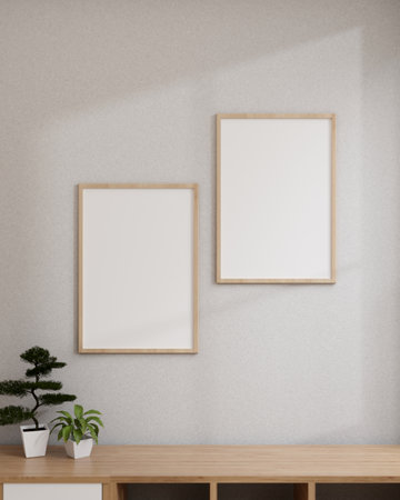 Minimal white room with blank picture frames mockup hanging on a white wall above a wooden bookcase....