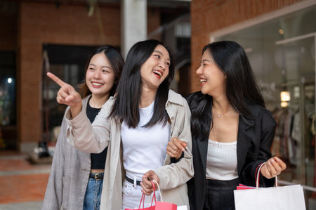 Group of attractive, fun Asian girls in trendy clothes are enjoying shopping in the city, walking with their shopping bags, spending a holiday weekend together. Fashion and lifestyle conceptsの写真素材