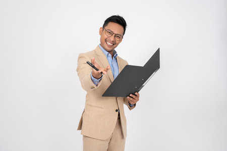 A positive, smart Asian businessman is standing on an isolated white background with a document...