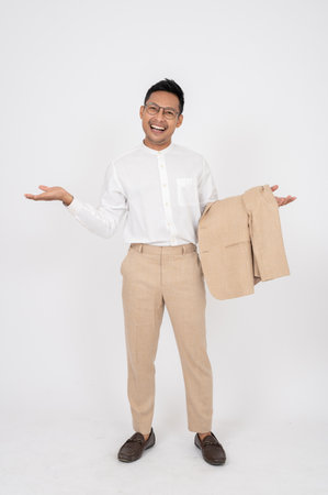 A smiling, handsome Asian businessman is opening his palms while standing on an isolated white background. showing options, recommendation, presentationの写真素材
