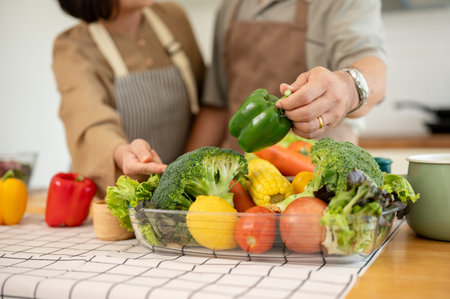 Close-up image of a lovely adult couple cooking in the kitchen together, preparing fresh vegetables and ingredients. healthy life, domestic life, leisureの写真素材