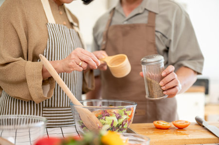 Happy Asian couples, husband and wife, are cooking a healthy salad bowl in the kitchen together,...