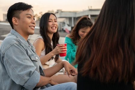 Group of happy young Asian friends partying on a rooftop bar restaurant, having fun, enjoying eating, and talking. celebration and city life conceptsの写真素材