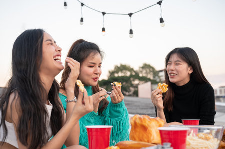 Group of cheerful young Asian female friends are laughing, enjoying talking and eating snacks while...