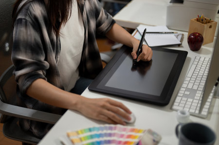 Close-up image of a professional female graphic designer illustrator artist working in the office, drawing something on a graphic tablet.の写真素材