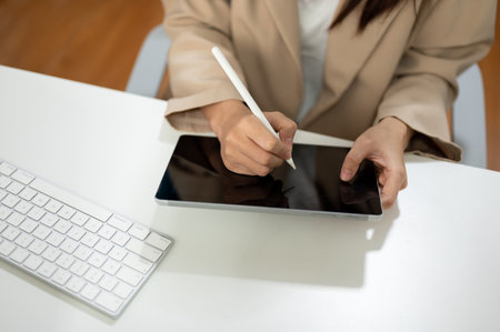 Close-up image of a businesswoman using her digital tablet at her office desk. People and technology conceptの写真素材