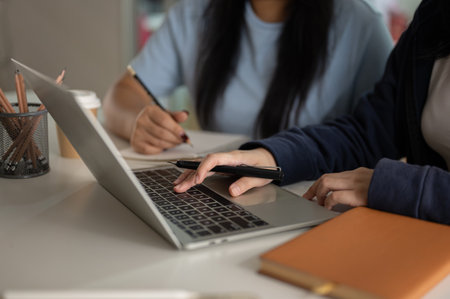 Cropped shot of two women are discussing work and checking the project on a laptop computer together in the office.の写真素材