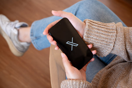 Chiang mai, Thailand - Jan 25 2024: A woman holding an iPhone with X Twitter logo on the screen. A...