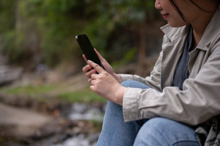 A cropped shot of an Asian woman using her phone, searching for information, or looking at the map...