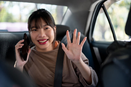 A happy young Asian female passenger is giving directions to a taxi driver. people and transportation conceptsの写真素材