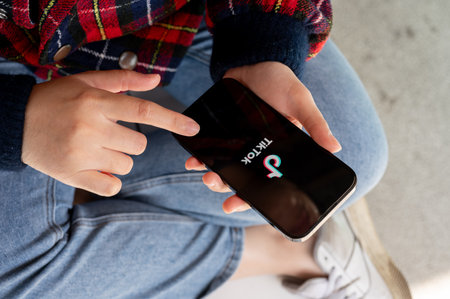 Chiang Mai, Thailand - Feb 01 2024: A woman using the TikTok application on her smartphone. The TikTok logo displayed on an iPhone 14 screen. people and social media platform conceptsのeditorial素材