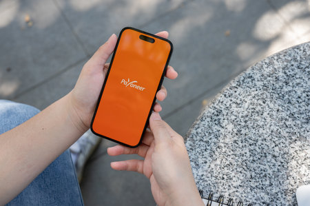 Chiang Mai, Thailand - Feb 02 2024: A close-up shot of a woman using the Payoneer application on her iPhone while sitting outdoor.のeditorial素材