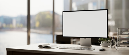 A modern office features a white-screen computer mockup and accessories arranged on a table near the...