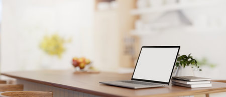 A white-screen laptop computer mockup on a wooden kitchen island tabletop in a modern bright kitchen. Home workspace, remote workplace. close-up image. 3d render, 3d illustrationの写真素材