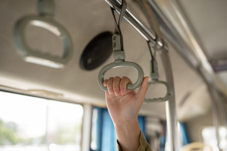 A close-up image of a woman hand holding a bus hanger while standing on a public bus. people and public transportation conceptsの写真素材