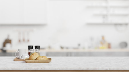 Marble counter top with empty space for display product, coffee mugs and a bread basket with blurred...