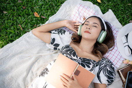 A beautiful Asian woman falls asleep or takes a nap while listening to music on her headphones and...
