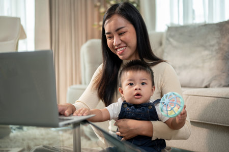 A positive Asian businesswoman mom is playing with and taking care of her little son while working...