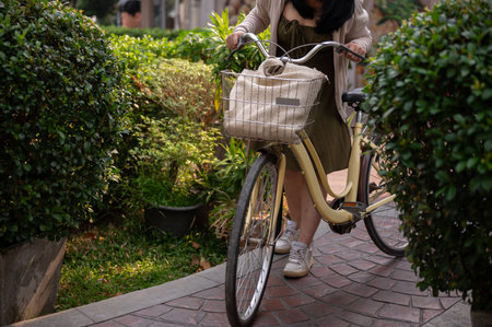 A cropped shot of a woman in a cute dress pushing her bicycle on a footpath in a city park. people and lifestyle conceptsの写真素材