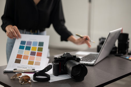 A close-up shot of a professional DSLR camera on a desk in a photoshoot studio. a female photographer working in a studio. selective focusの写真素材