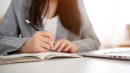 A cropped shot of a businesswoman in a business suit is working at her desk, focused on writing or taking notes in the notebook with a pencil. businesspeople conceptの写真素材