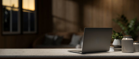 A laptop computer on a desk in a contemporary living room in the evening. place of work concept. a...