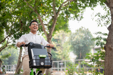 A happy, carefree Asian millennial businessman is on a bike in the park, riding a bike to work in the morning. businesspeople and transportation conceptsの写真素材