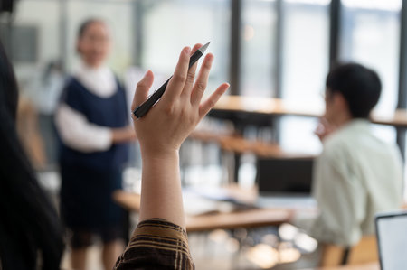 A close-up image of a student raising her hand, asking or answering a question while studying in the classroom. university, high school, education conceptの写真素材