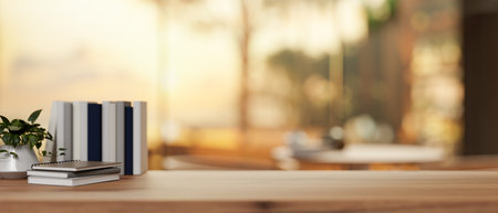A wooden tabletop with books, a decor plant, and a display space to showcase products against a blurred background of a sunset view in a restaurant. close-up image. 3d render, 3d illustrationの写真素材