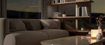 The interior design of a contemporary living room at night with dim light, a cozy couch against the window near a book shelf and a lamp on a coffee table. 3d render, 3d illustrationの写真素材