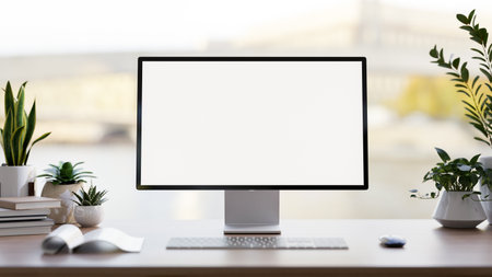 A front view image of a computer white-screen mockup, a keyboard, books, and potted plants on a desk...