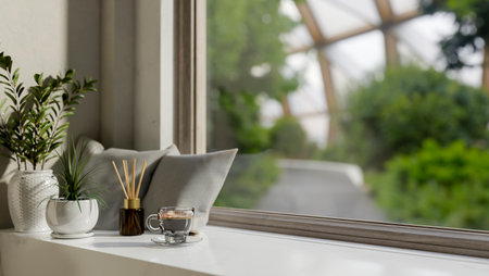 A close-up image of a white window sill or window board featuring a coffee cup, pillows, a reed diffuser, and potted plants in a modern, minimal living room. 3d render, 3d illustrationの写真素材