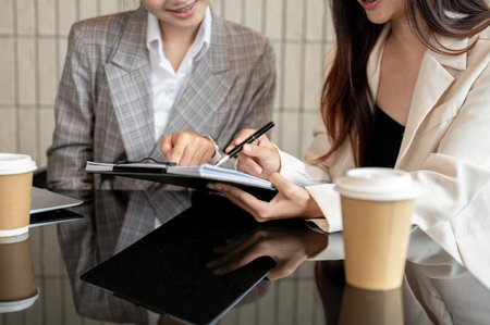 A cropped image of two businesswomen or female office workers are checking the documents, having a meeting, discussing work, and working on an assignment together in the meeting room.の写真素材