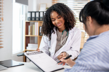 A confident Black female doctor handing a medical record to a patient to check during a medical consultation in the examination room at the hospital.の写真素材