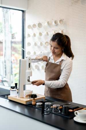 An experienced, beautiful young Asian female barista in an apron is making a coffee with a modern coffee machine in a minimal white cafe. coffee shop business, small business, part time jobの写真素材