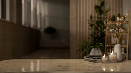 A copy space for displaying products on a neutral marble tabletop features candle lights, books, and...