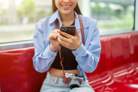 A cropped image of a beautiful young Asian woman tourist using her smartphone, reading messages or...