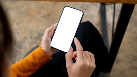 A close-up image of a woman sitting indoors and using her smartphone. a smartphone with a...