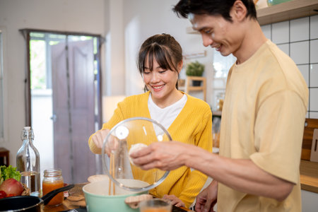 A lovely young Asian couple is enjoying making noodles together in the kitchen, spending happy moments at home. domestic life and couples conceptsの写真素材