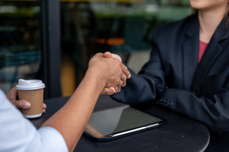 A close-up hand image of an Asian man is shaking hand with his insurance agent after their meeting at a coffee shop. partnership, colleague, teamwork, business dealingの写真素材