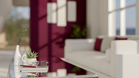 A close-up image of a modern mirror glass coffee table featuring book, eyeglasses, a pencil, and...