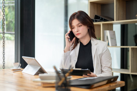 A professional Caucasian businesswoman or female manager is discussing business on the phone with a client while sitting at her desk in the office.の写真素材