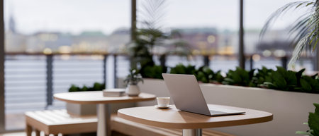 A laptop on a wooden table in a contemporary minimalist coffee shop or restaurant with a stunning...