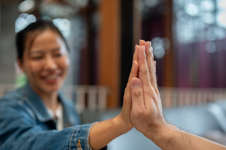 A close-up of two people giving each other a high five during a meeting at a coffee shop....