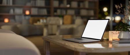 A close-up side view of a laptop with a white screen mockup on a coffee table in a contemporary living room, illuminated by warm lighting. 3d render, 3d illustrationの写真素材