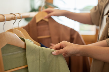 A close-up of two female friends selecting clothes from a rack, enjoying their shopping experience together in a store. lifestyles, fashion, and peopleの写真素材