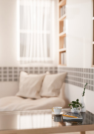 A close-up of a modern coffee table in a bright, minimalist living room, featuring a book, a pencil,...