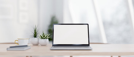 A close-up of a laptop with a white screen mockup, a book, a pencil, a coffee cup, and decorative plants on a wooden table in a bright room. workspace, place of work, 3d render, 3d illustrationの写真素材