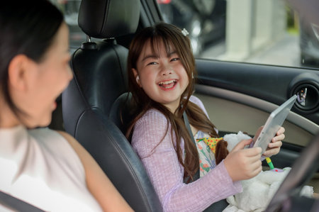 A young, adorable Asian girl happily chats with her mom during their family trip or on the way to...