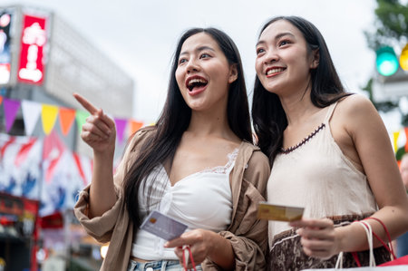 Two cheerful Asian female friends are excited and amazed by the various food stalls, holding their...